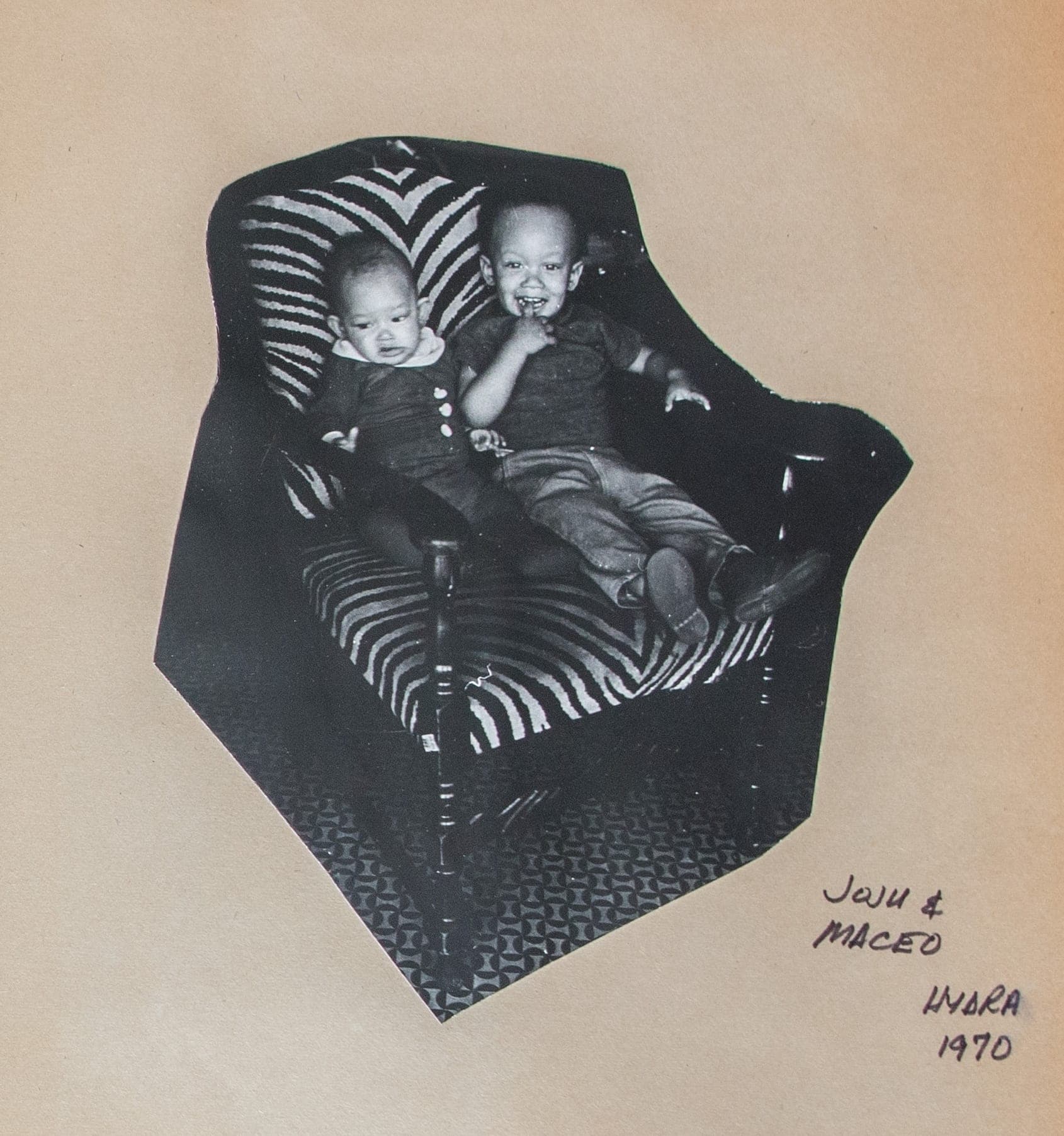 Black-and-white photograph of Joju and Maceo Cleaver seated in a zebra-striped armchair, Hydra, 1970, mounted on a family album page